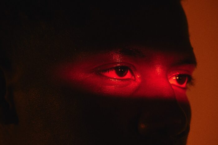 Man peeking into a room lit by red lighting