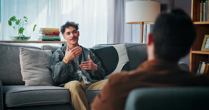 Man sitting on couch speaking with his therapist